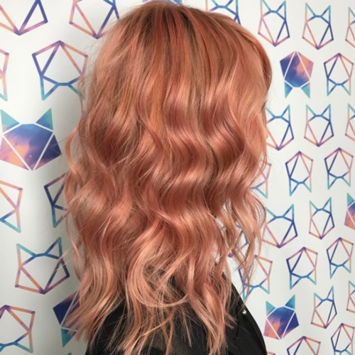 Mujer de cabello peinado en ondas y teñido en peachy copper
