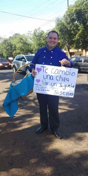 Chico con letrero intercambiando hamburguesas por juguetes para niño indígenas