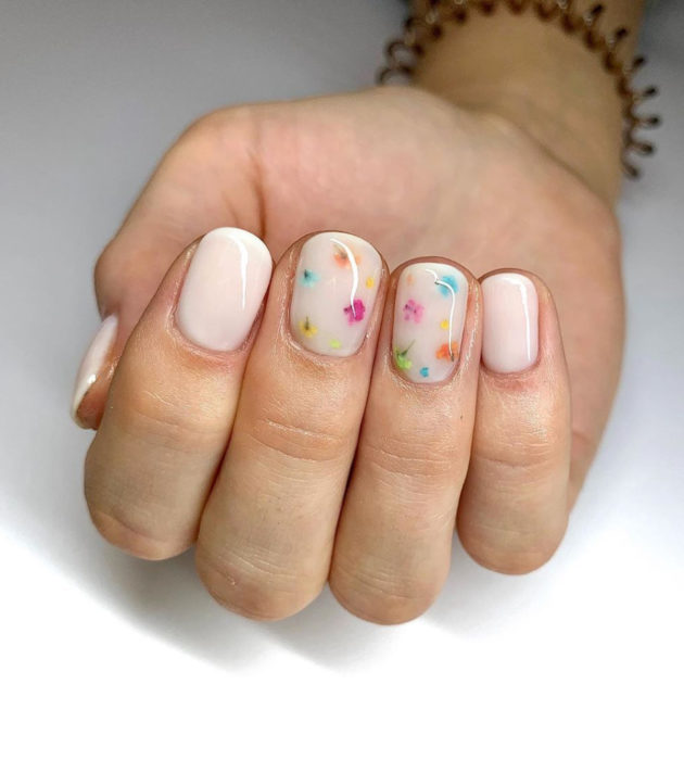 Diseños de manicura milk bath; uñas cortas color blanco con colores pequeños azules, amarillos, anaranjados, verdes y rosas