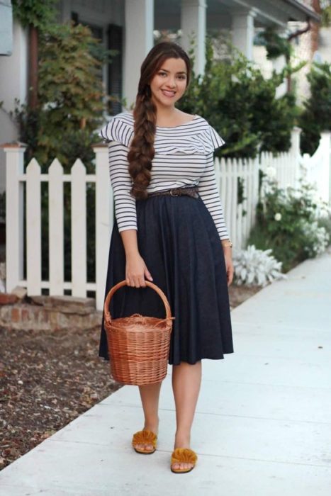 Mujer con blusa de rayas blancas y azules, falda larga y bolso tipo canasta