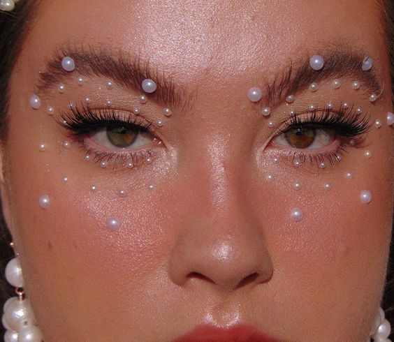Mujer rubia con maquillaje luminoso y perlas
