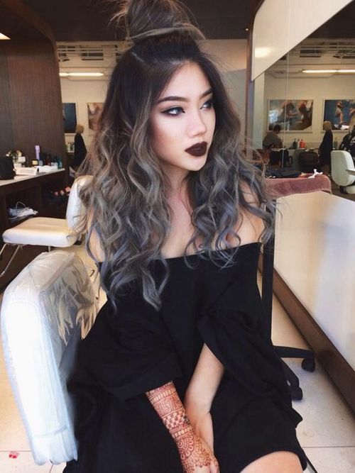 Chica sentada en una silla mostrando su cabello largo teñido con silver highlights