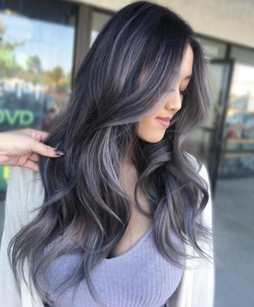 Chica de perfil mostrando su cabello largo y ondulado teñido con silver highlights