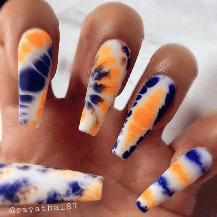 Manicura estilo tie dye en tono morado, anaranjado y blanco