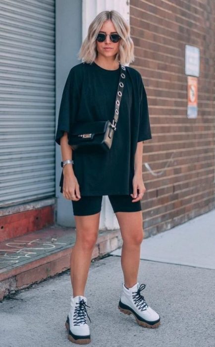 Chica rubia con cabello suelto usando blusa y shorts de ciclista color negros