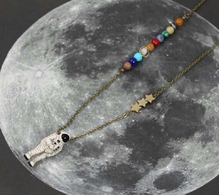Collar inspirado en el universo con el sistema solar, algunas estrellas y un astronauta