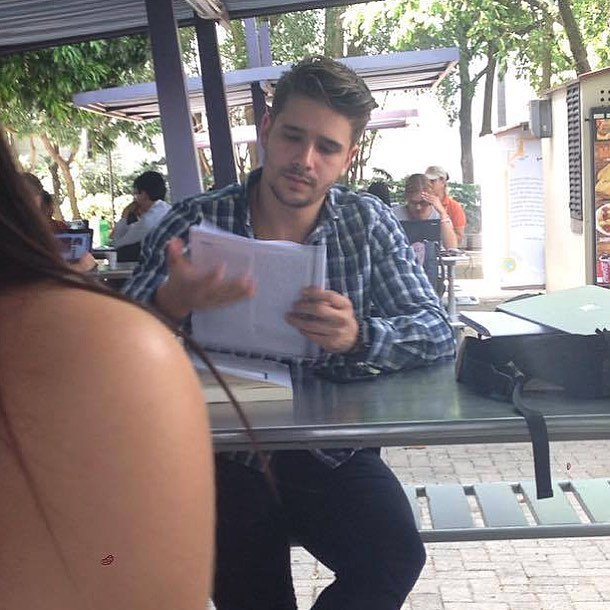 Chico con camisa a cuadros leyendo en el patio de la escuela