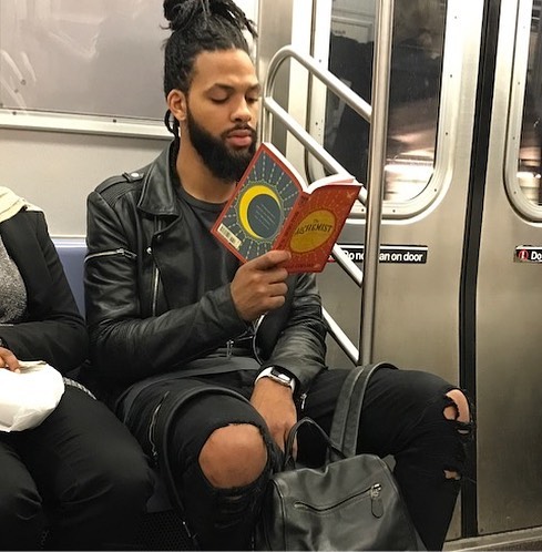 Hombre con jeans rotos leyendo dentro del metro