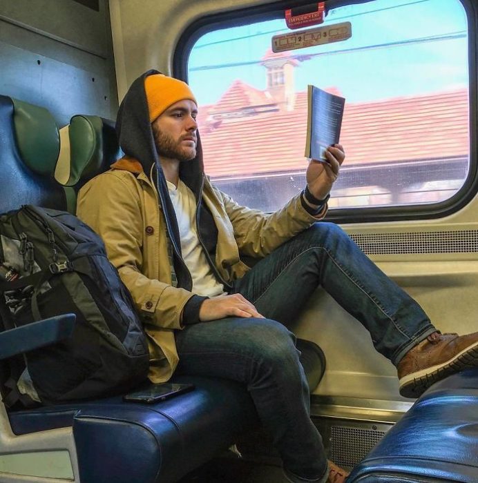 Hombre con chaqueta amarilla mostaza leyendo dentro del metro