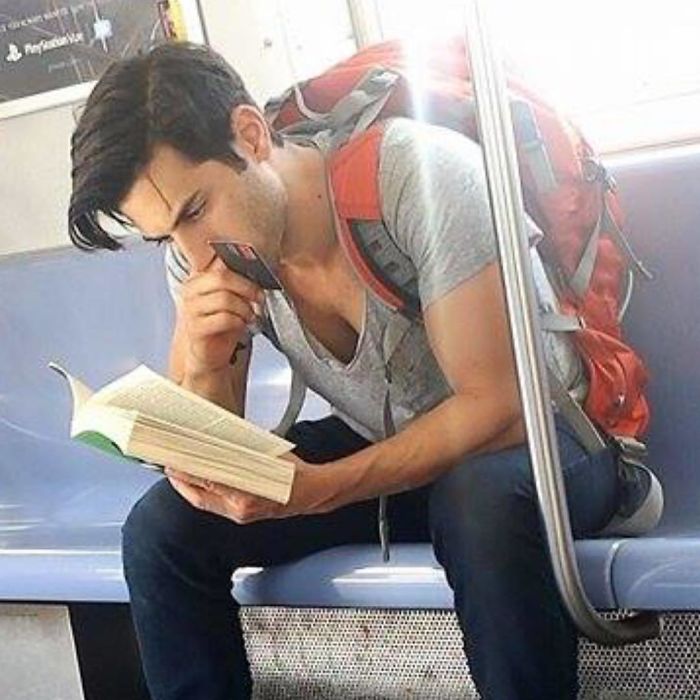 Hombre sentado en el asiento del metro leyendo un libro