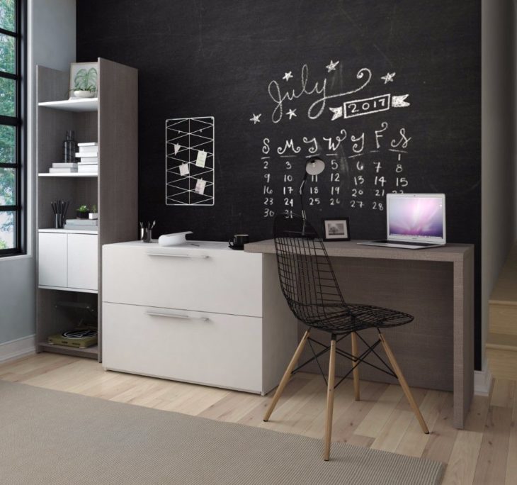 Escritorio con estilo minimalista, con cajones y repisas y pared negra para tiza y silla de red