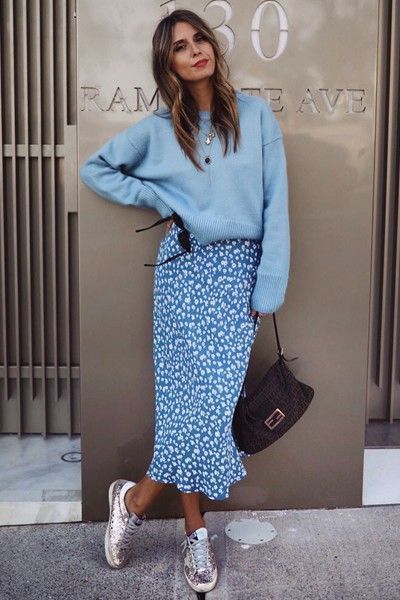 Chica de cabello largo y castaño con blusa midi y suéter de color azul y tenis metálicos