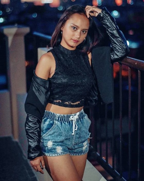 Rita Gaviola posando con short de mezclilla y chaqueta de cuero en un balcón 