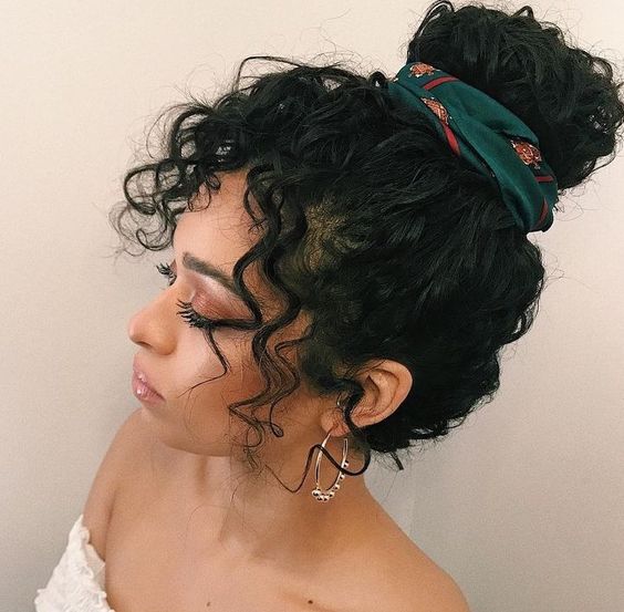 Chica morena de cabello rizado con recogido alto decorado con un pañuelo