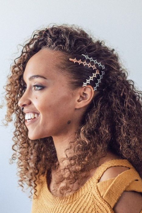 Chica morena de cabello rizado con broches laterales sujetando su cabello