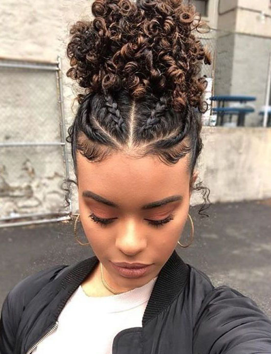 Chica de cabello rizado con trenzas y torciditos recogidos en un chongo