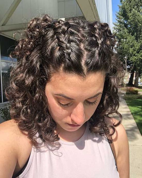 Chica de cabello rizado con dos trenzas alemanas en la parte superior de la cabeza