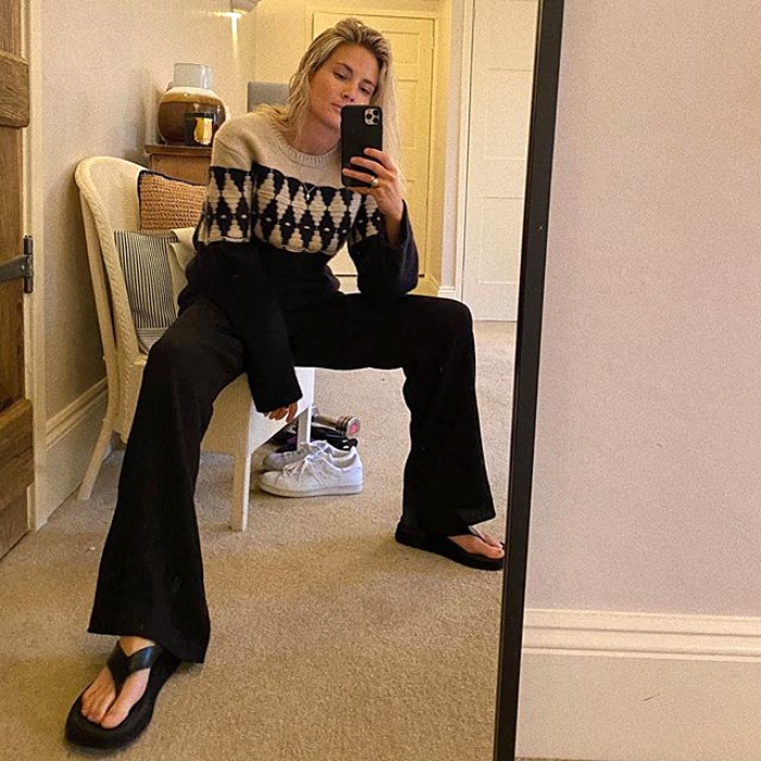 chica rubia con suéter negro y blanco, pantalones de vestir acampanados y sandalias negras