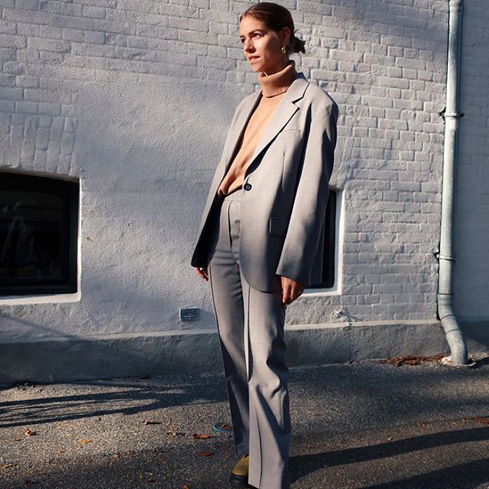chica rubia usando un top beige, blazer gris y pantalón gris de vestir