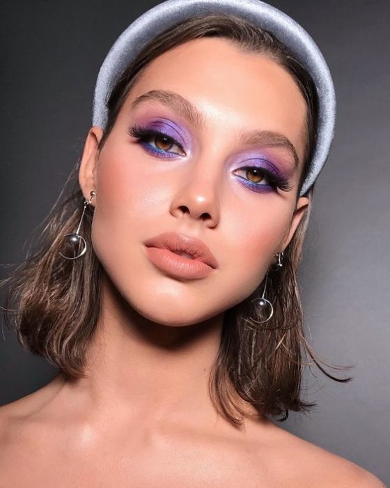 Modelo con sombras de ojos moradas y diadema gris grande