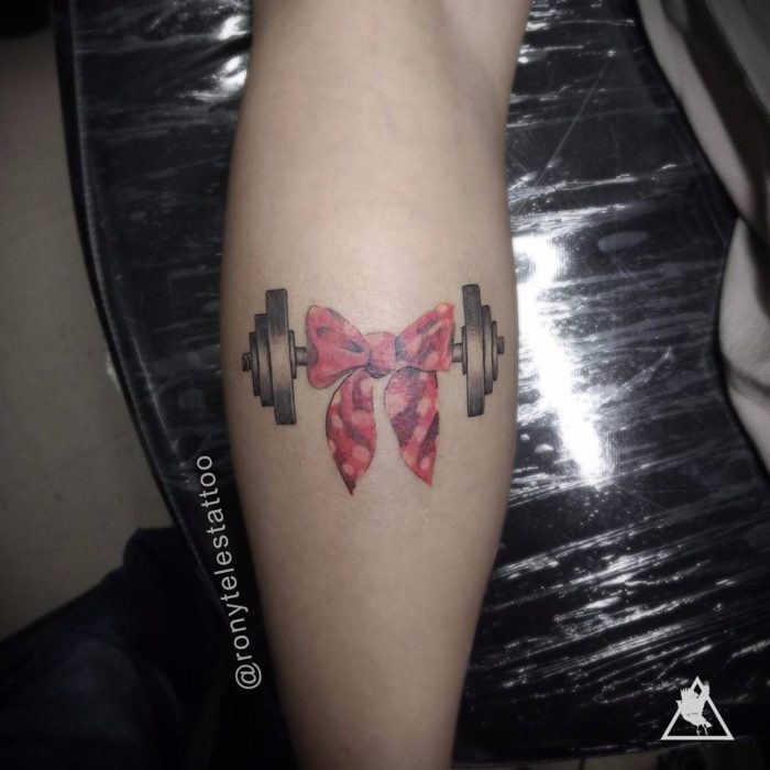 Chica con un tatuaje en el brazo de unas pesas