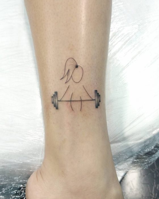 Chica con un tatuaje en el brazo de una niña cargando una pesa