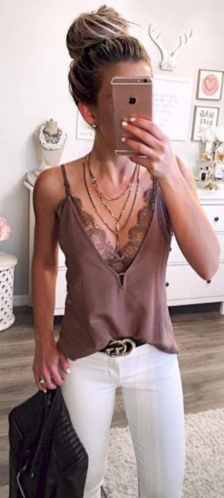 Chica usando una camisa de color rosa con un pantalón blanco mientras se toma una selfie