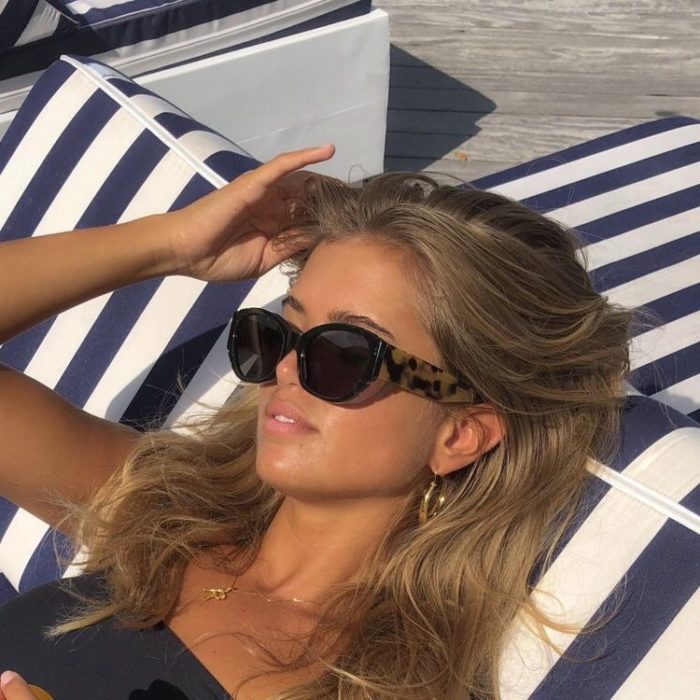 Chica rubia bronceándose con gafas de sol