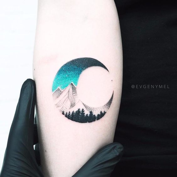 Tatuaje de una media luna con un paisaje interior de las montañas