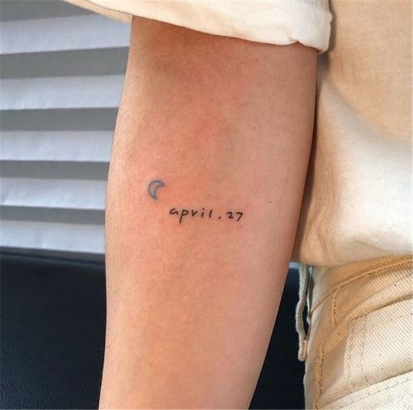 Tatuaje con una media luna azul y una fecha de nacimiento