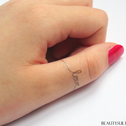 Chica con un tatuaje de Love en su dedo pulgar