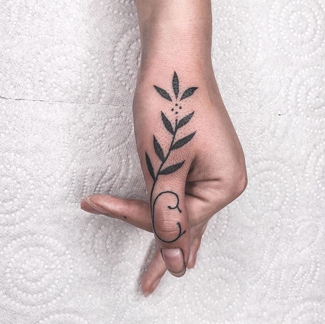 Chica con un tatuaje de unas hojas en el dedo pulgar
