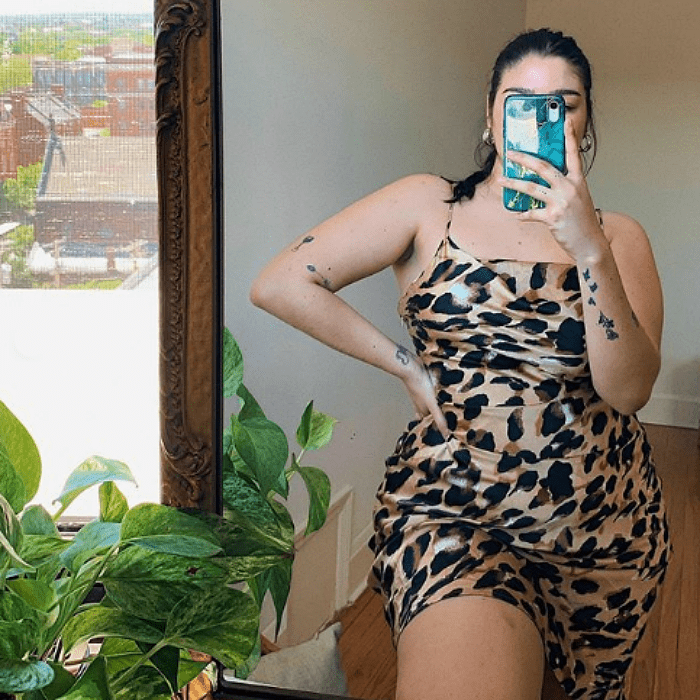 chica de cabello negro tomandose una selfie frente al espejo usando un vestido de satén con estampado de animal print talla extra