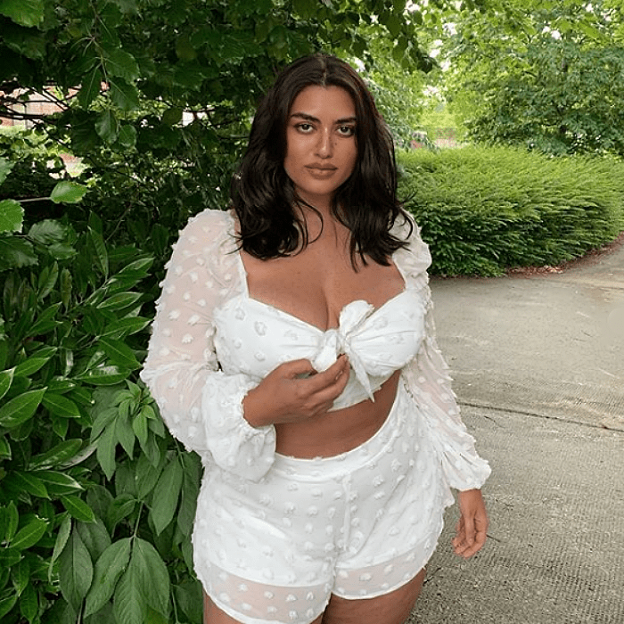 chica curvy de talla extra con un conjunto blanco de blusa de manga larga y escote en v, shorts con vuelo y encanje