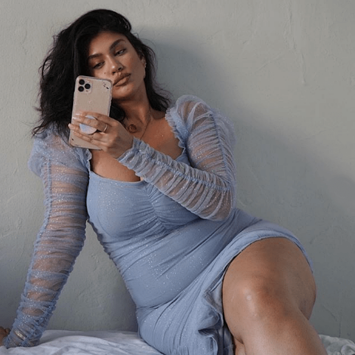 chica morena curvy con vestido de talla extra ceñido color azul lila claro
