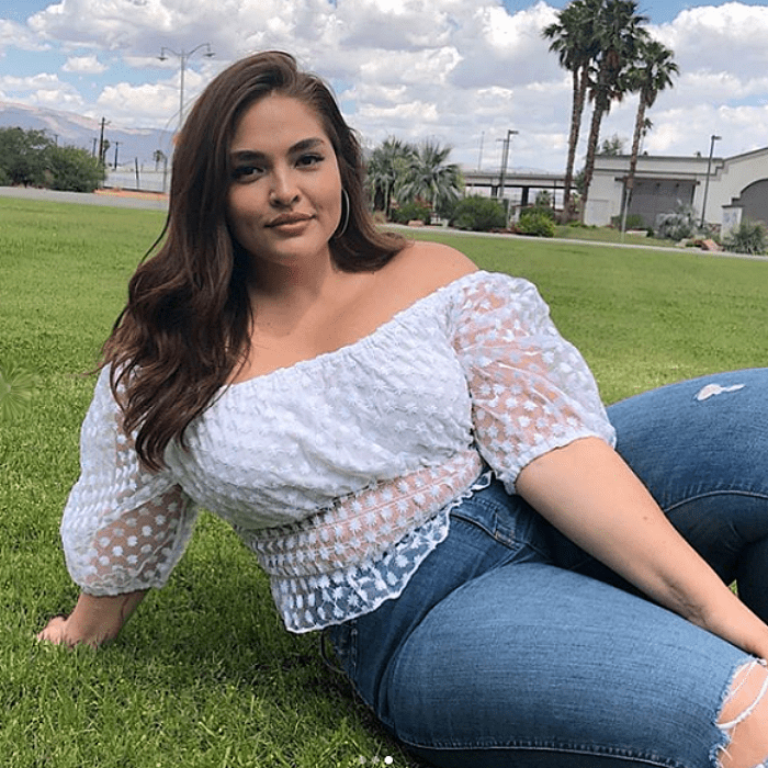 chica de cabello castaño, de talla extra usando una blusa con mangas de globo y jeans desgastados