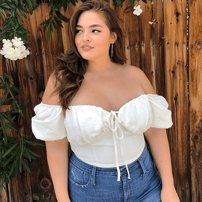 chica curvy de talla extra usando una blusa blanca de manga corta, cuello en v tipo bustier y jeans
