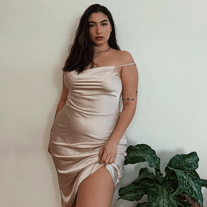 chica curvy talla extra con cabello castaño largo usando un vestido tipo slip de satén color champán