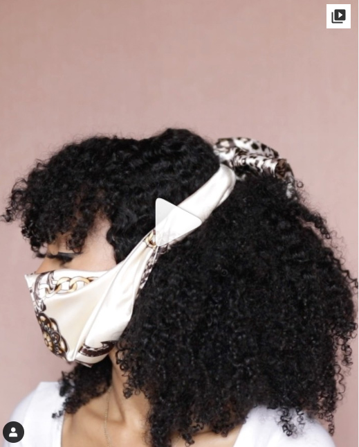 Chica de cabello rizado mostrando cómo sujetar una mascarilla