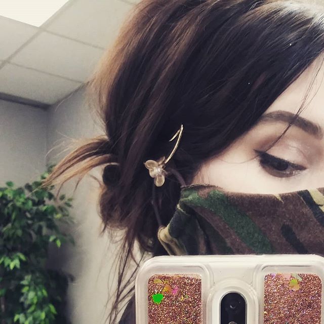 Chica tomando una selfie mientras muestra cómo sujeta su cubreboca