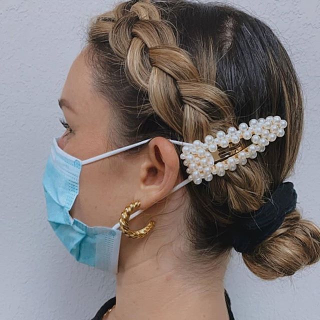 Chica sujetando una mascarilla con un par de broches