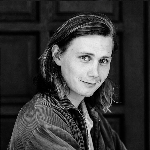 Moritz Jahn, actor alemán en la serie Dark, posando de perfil y sonriendo ligeramente