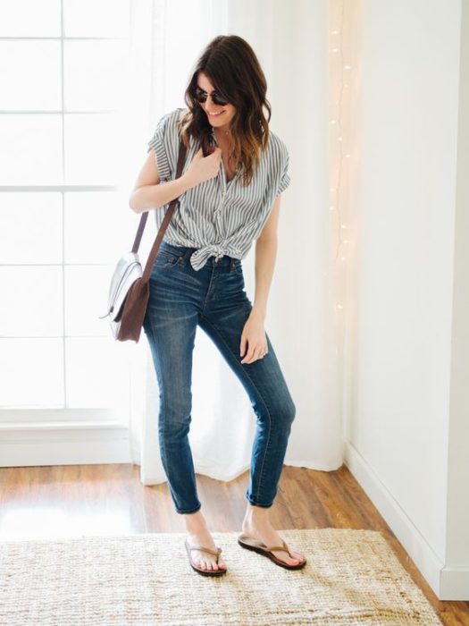 Chica posando con jeans oscuros, blusa gris y flip flops negros