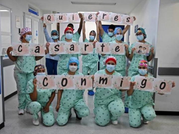 Personal médico sosteniendo letrero de propuesta de matrimonio