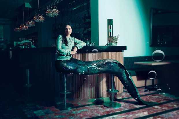 Escena de la película The Lure con una sirena sentada sobre los bancos de un bar