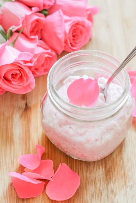 Frasco de cristal con crema hidratante y pétalos de rosas