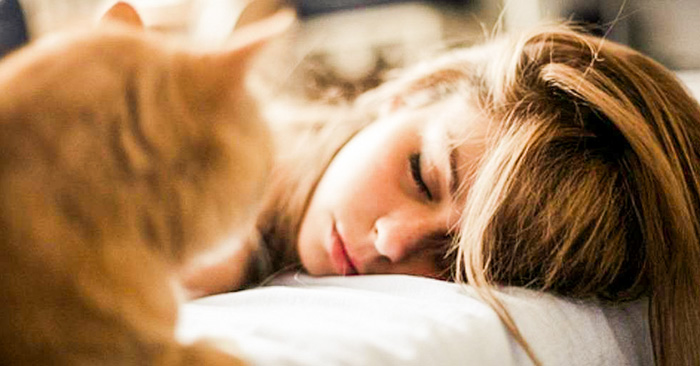 Chica dormida junto a su gato después de usar agua de rosas