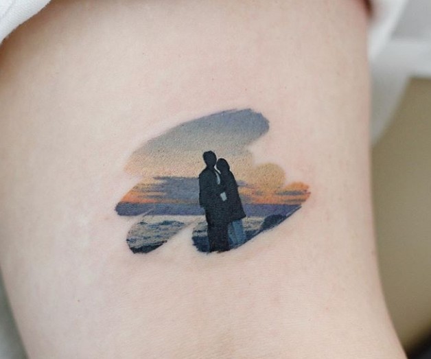 Tatuaje de una pareja viendo el atardecer en la playa