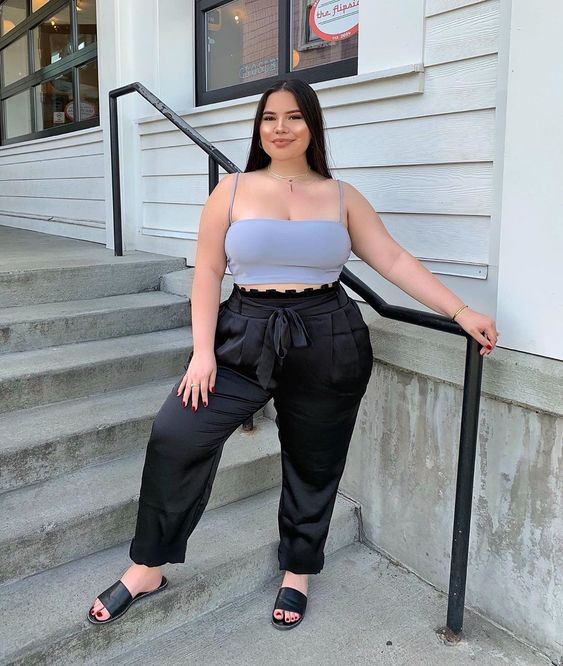 Chica curvy con top lavanda de tirantes y pantalón negro