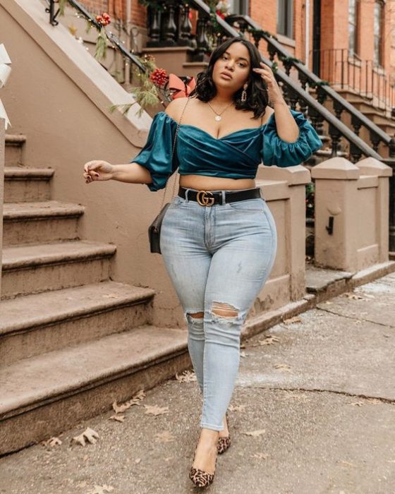 Chica curvy de melena corta con jeans rotos y blusa de satén verde